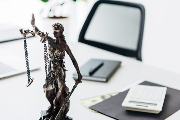 selective focus of statuette of justice near money on table in office